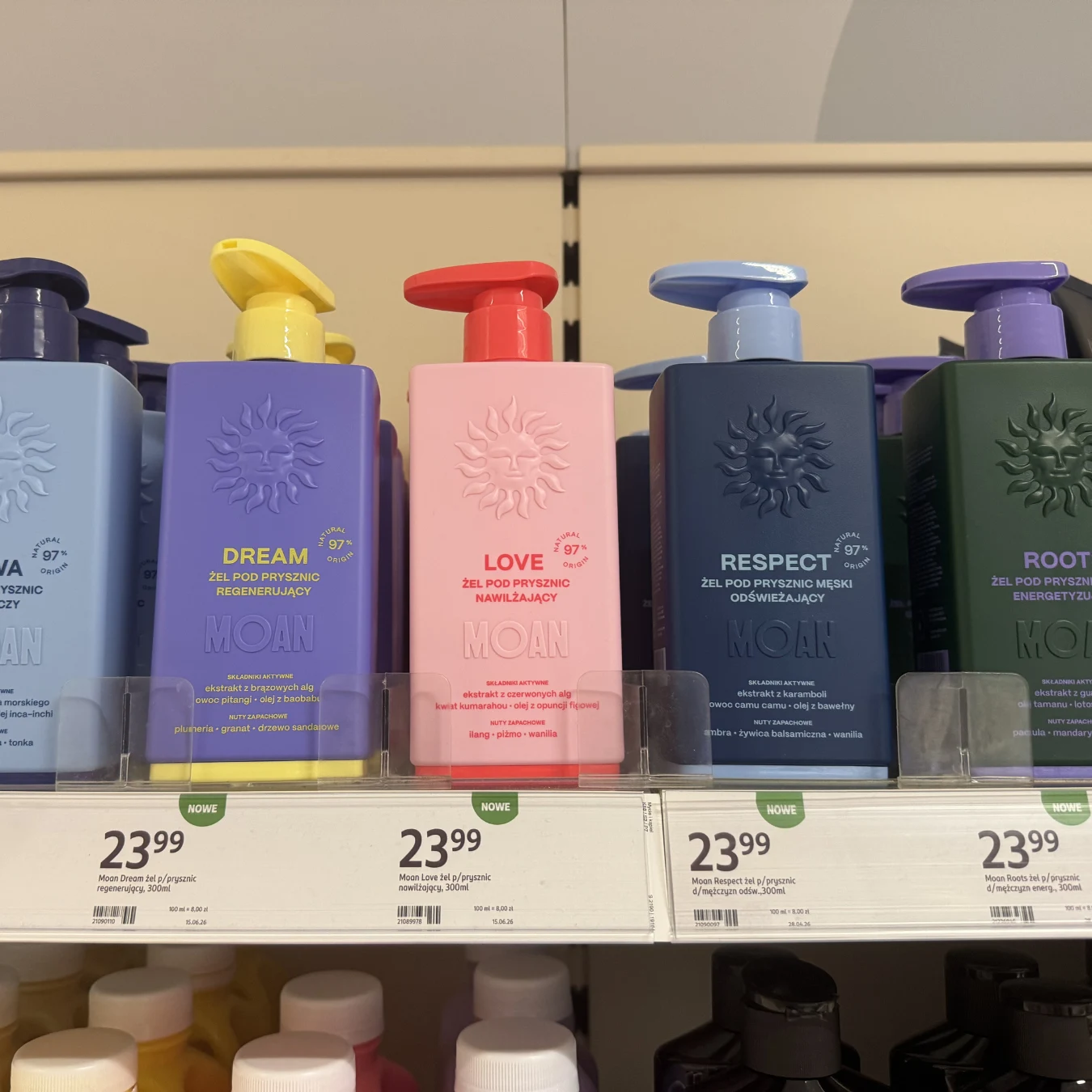 Rząd kolorowych butelek żeli pod prysznic z różnymi napisami i przeznaczeniem, ustawionych na sklepowej półce z widocznymi cenami pod każdym produktem.