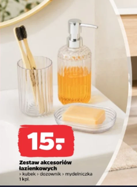 Szklany kubek z dwoma szczoteczkami, przezroczysty dozownik z pompką wypełniony mydłem w płynie oraz przezroczysta mydelniczka z kostką mydła ustawione na białej łazienkowej półce.