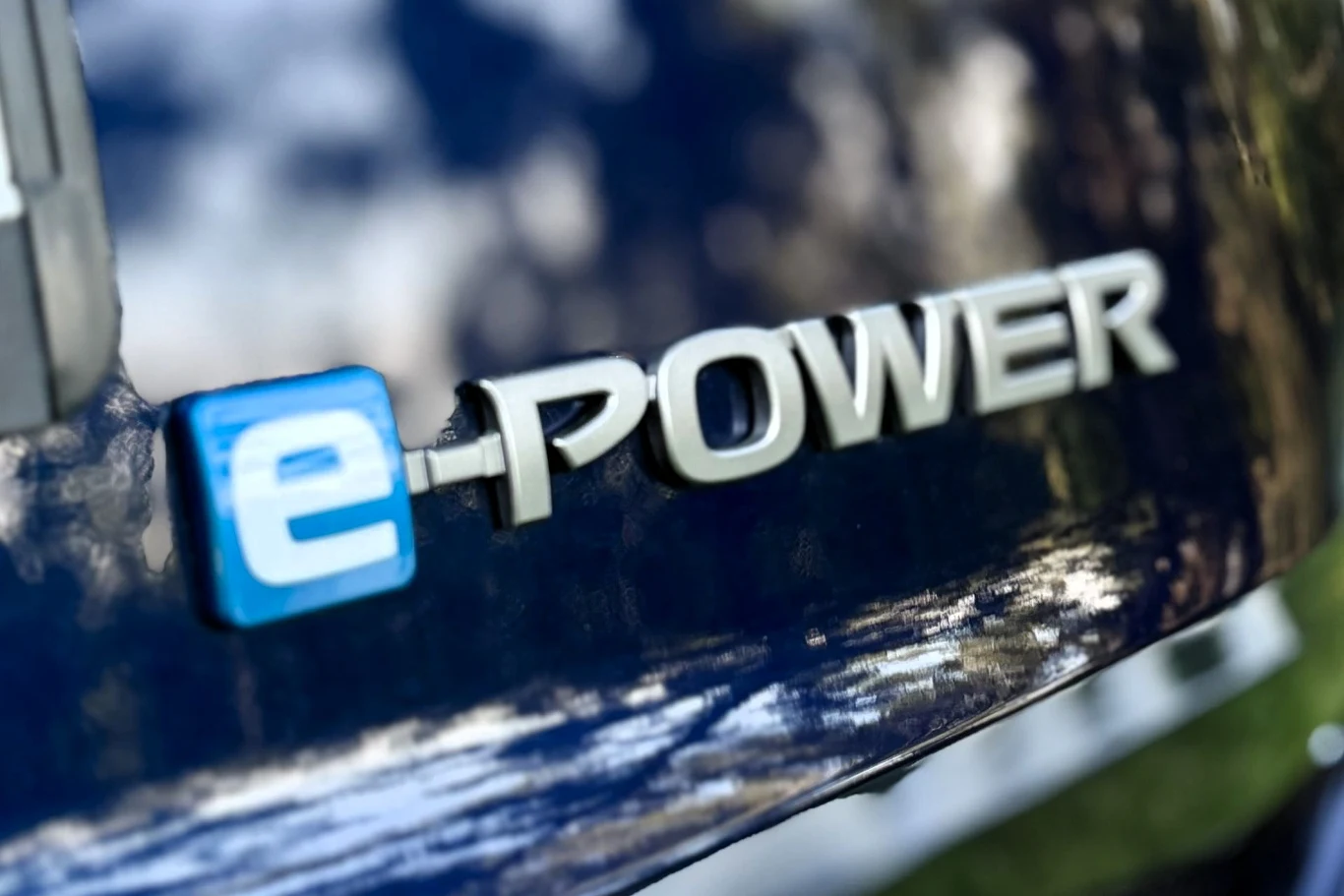 Emblemat e-POWER umieszczony na karoserii samochodu, wskazujący na zastosowanie technologii hybrydowej lub elektrycznej w pojeździe.
