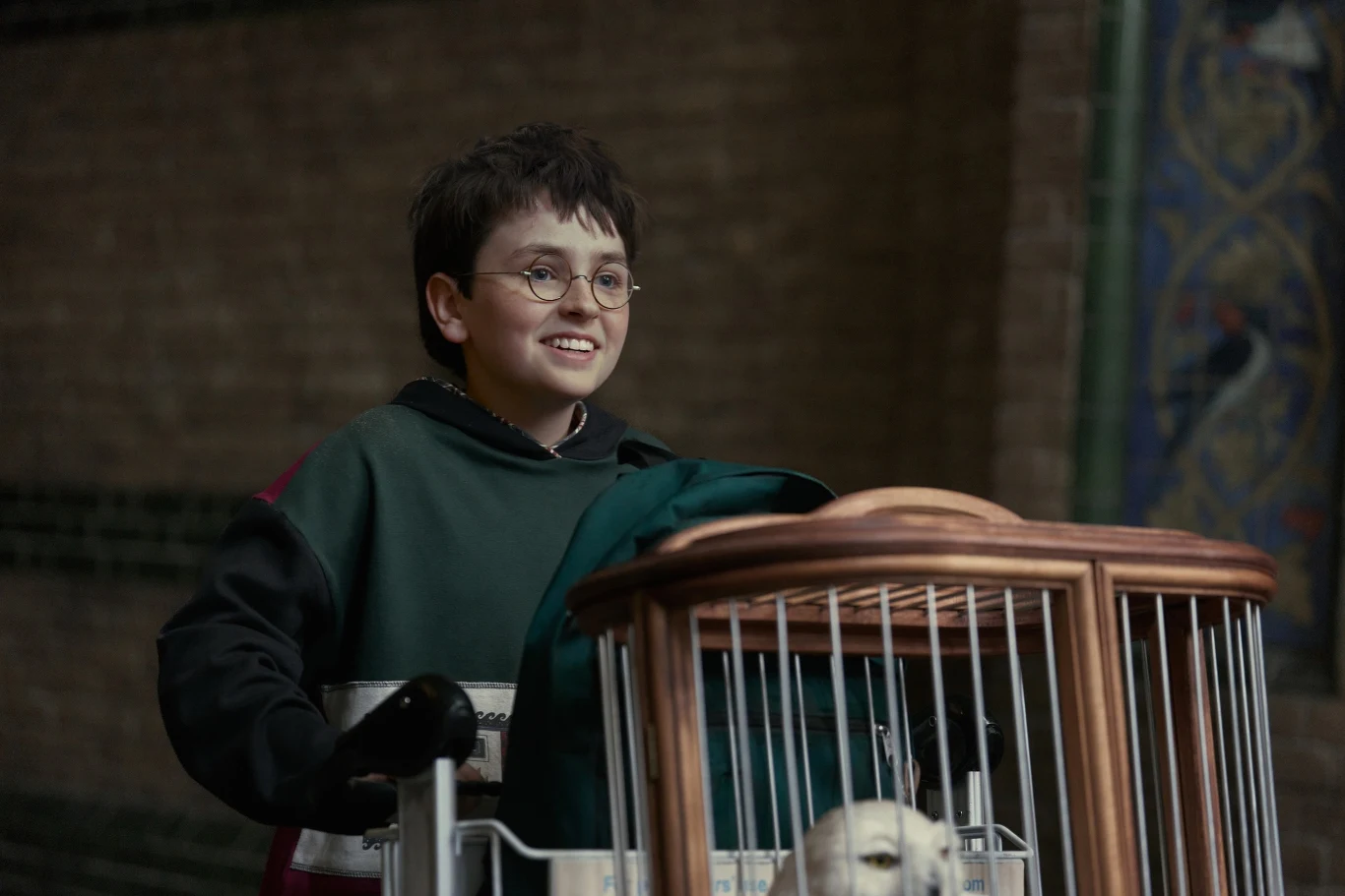 Dominic McLaughlin w serialu HBO MAX "Harry Potter" Dominic McLaughlin jako Harry Potter pcha wózek z klatką i białą sową w serialu HBO MAX "Harry Potter".