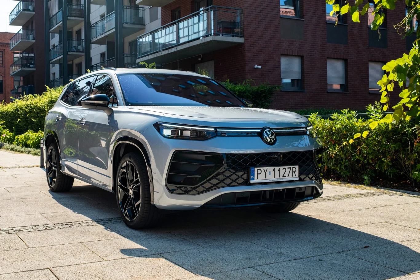 Srebrny SUV marki Volkswagen z nowoczesnym, dynamicznym designem zaparkowany na tle nowoczesnej zabudowy mieszkalnej.