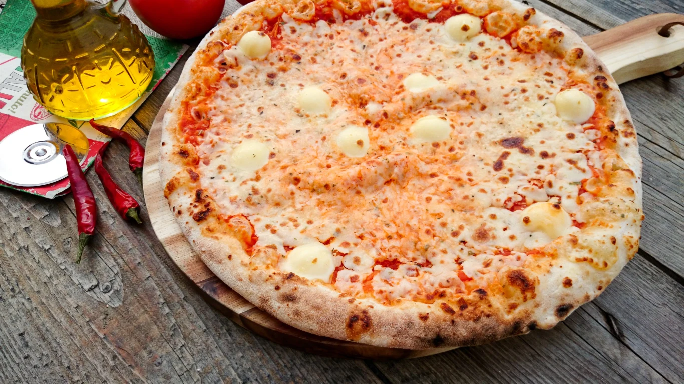Pizza serowa o apetycznie zarumienionym cieście, pokryta rozpływającym się serem mozzarella oraz miejscowymi plamkami aksamitnego sera, podana na drewnianej desce.