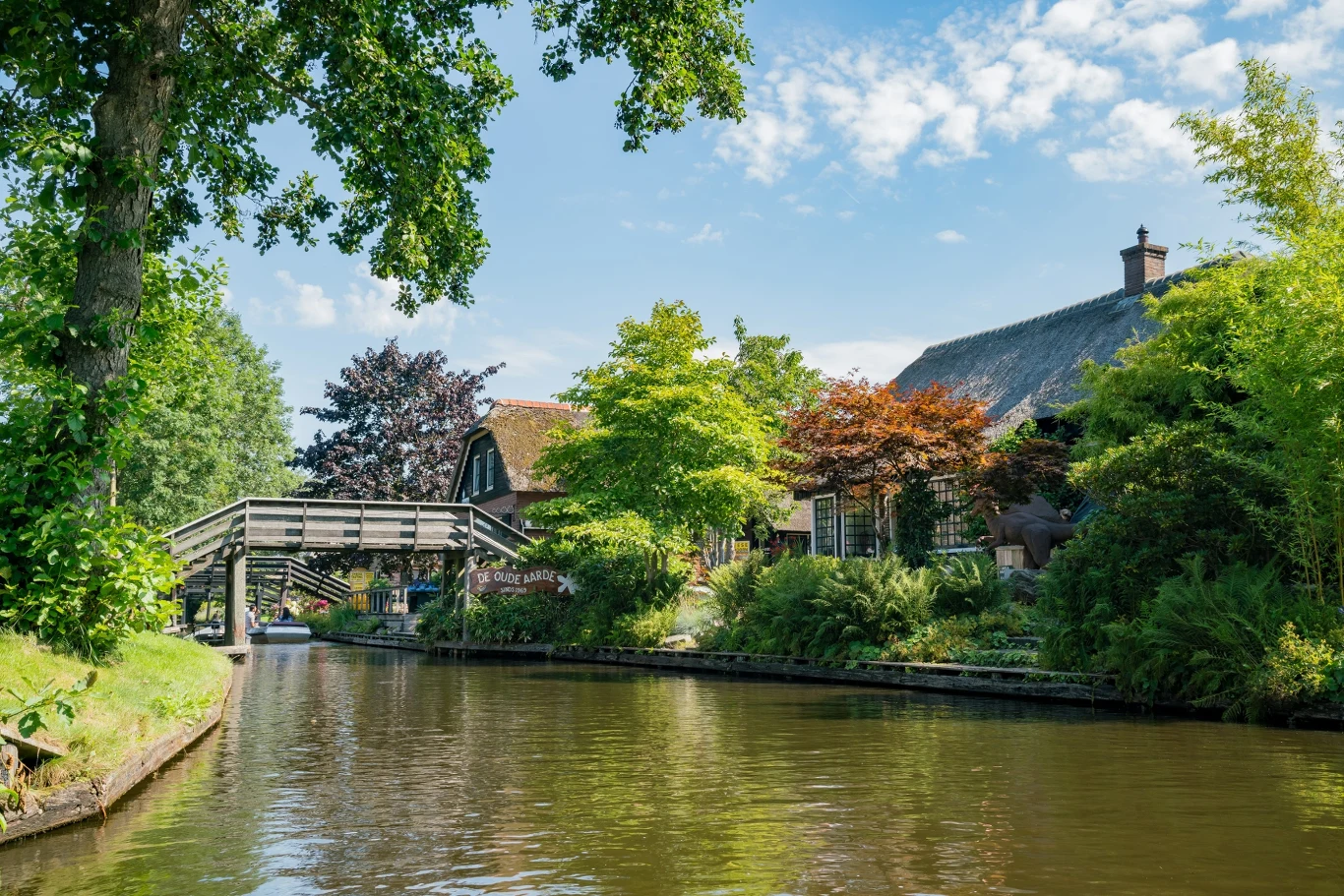 Giethoorn nazywany jest Wenecją Północy. To wyjątkowe, malownicze miejsce Kanał wodny w Giethoorn otoczony zielenią, drewniany most i dom kryty strzechą z ogrodem.