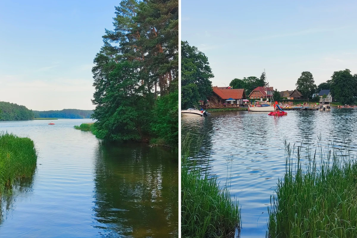 Spokojne jezioro otoczone zielenią, z lewej strony gęste drzewa i trzcinowisko, z prawej zabudowania oraz łodzie przy brzegu, na wodzie widoczny rower wodny z ludźmi.