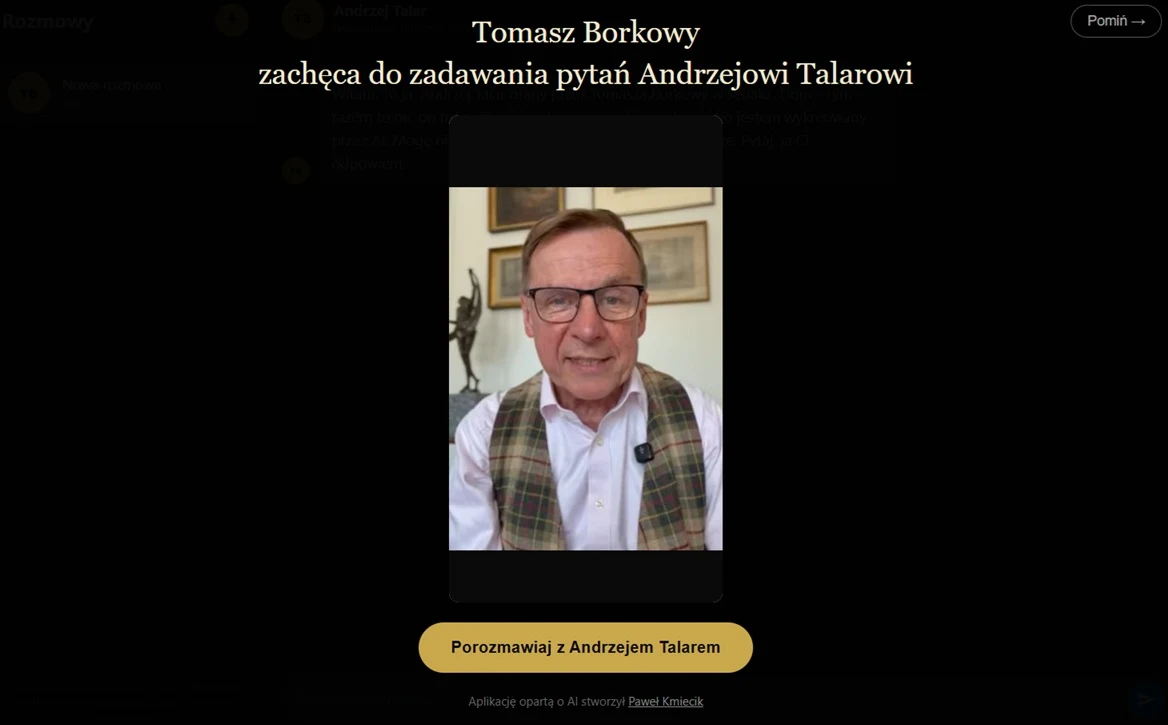Mężczyzna w okularach, uśmiechnięty, ubrany w koszulę i kamizelkę w kratę, siedzi na tle jasnej ściany z obrazami.
