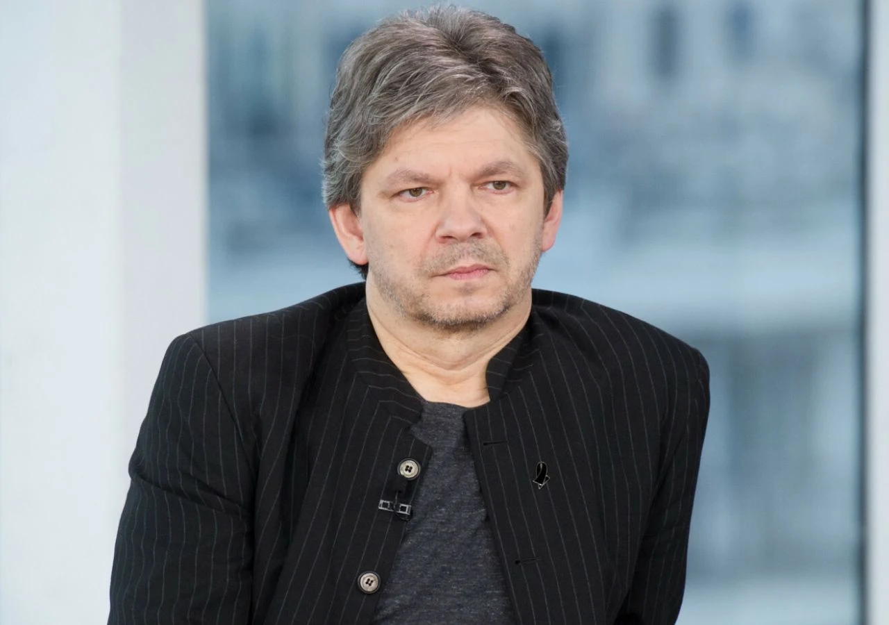 Filip Łobodziński Dziennikarz, tłumacz i muzyk Filip Łobodziński w czarnej marynarce i szarej koszulce.