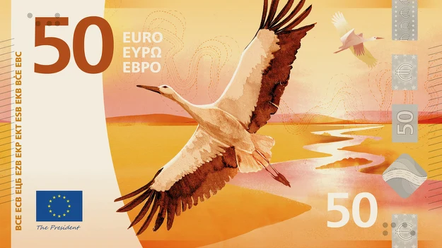 Bocian lecący nad rozlewiskami w ciepłych kolorach zachodzącego słońca, srebrne elementy zabezpieczające i nominał 50 euro na tle europejskich oznaczeń.