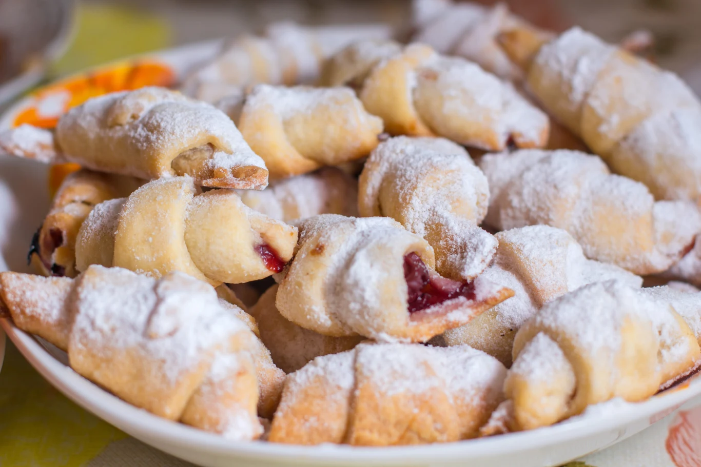 sweet cookies with jam Talerz z kruchymi rogalikami z owocowym nadzieniem i cukrem pudrem na wierzchu.