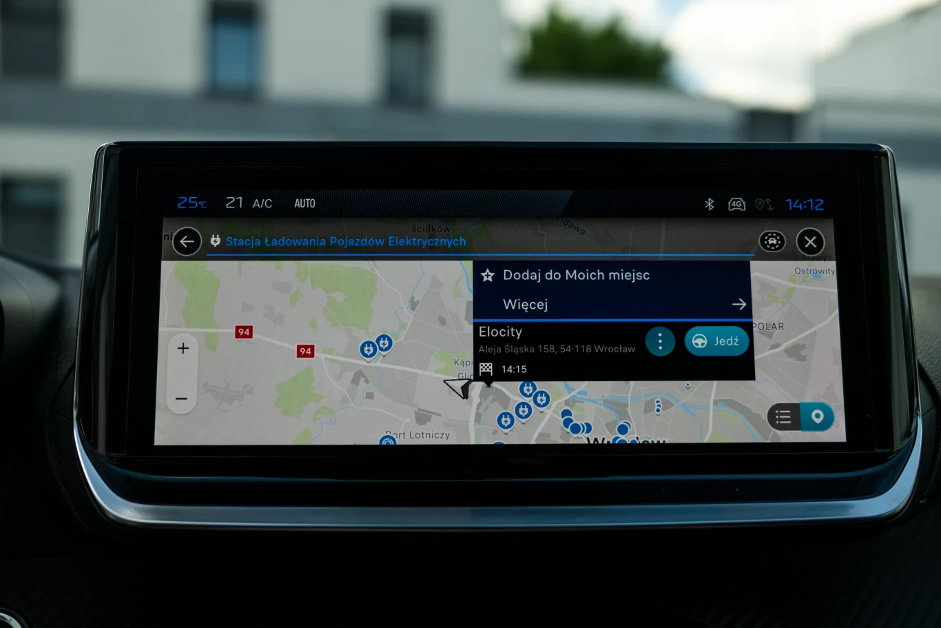 Ekran nawigacji samochodowej z aplikacją pokazującą mapę Wrocławia oraz lokalizacje stacji ładowania pojazdów elektrycznych, z wyróżnionym punktem Ełocity przy Alei Śląskiej 1/18.