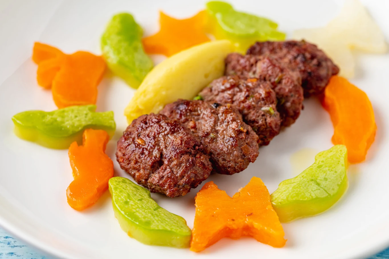 Grillowane kotleciki z grilla - idealna propozycja dla dzieci i dorosłych Trzy grillowane kotleciki mielone z purée ziemniaczanym i kolorowymi warzywami w kształcie zwierzątek i roślin.