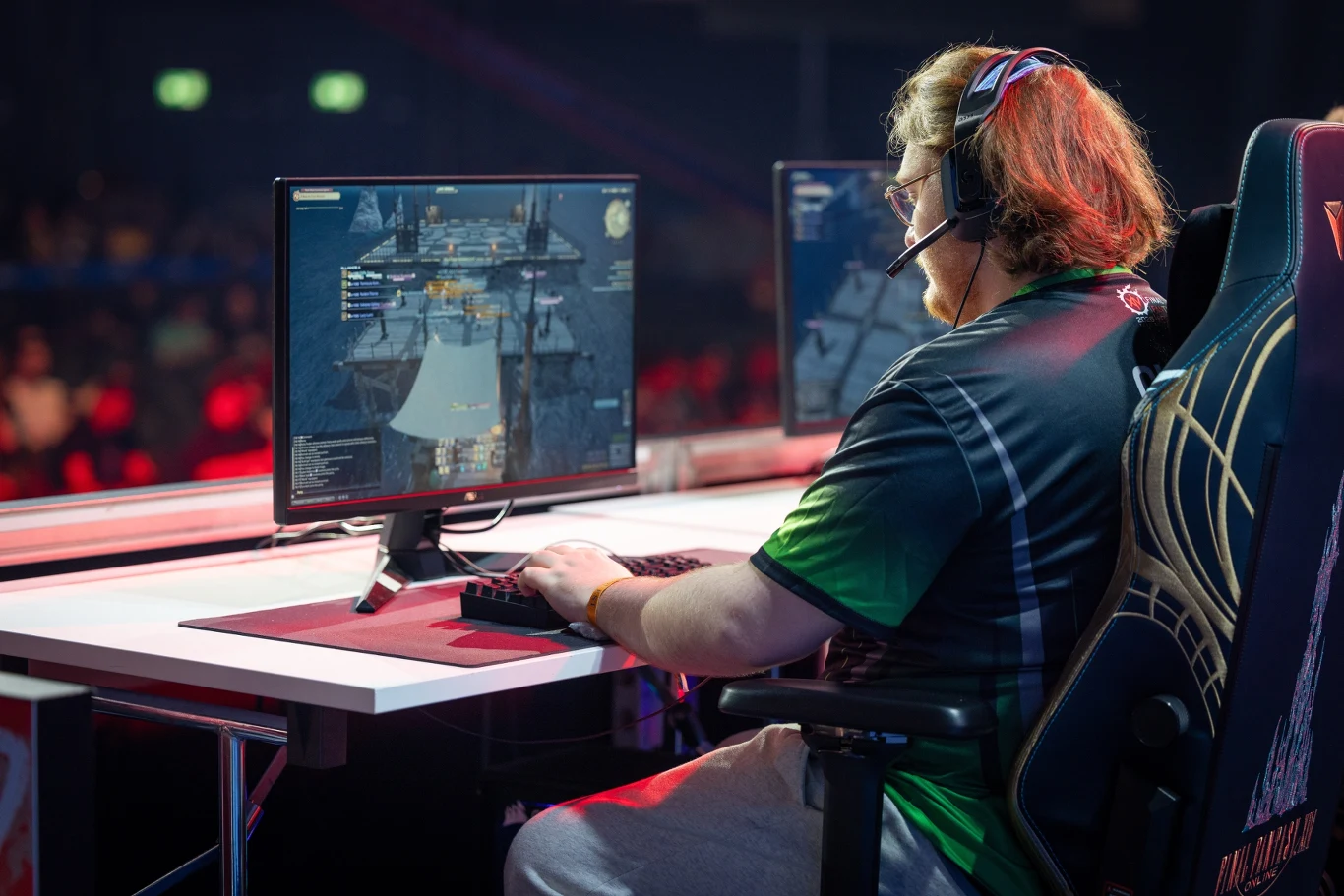 Gracz e-sportowy w słuchawkach rywalizuje przy komputerze, skupiony na rozgrywce wyświetlanej na monitorze podczas turnieju gamingowego.