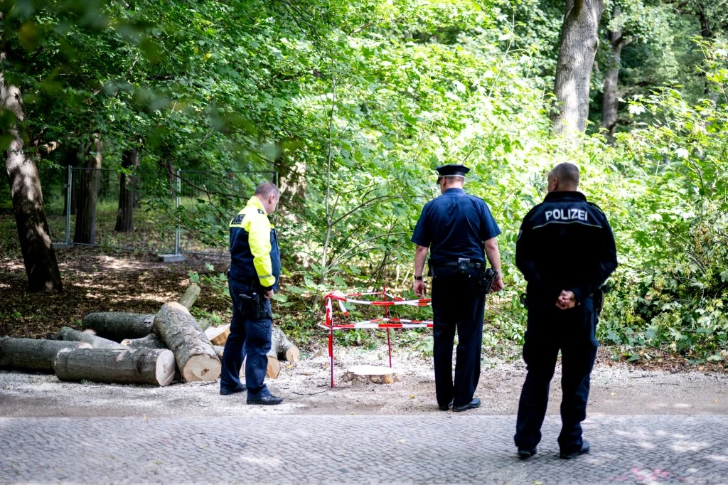 Niemcy zastanawiają się, jak mogło dojść do tragedii w Berlinie Trzech niemieckich policjantów obserwuje ogrodzony taśmą teren przy lesie, obok leżą ścięte drzewa.