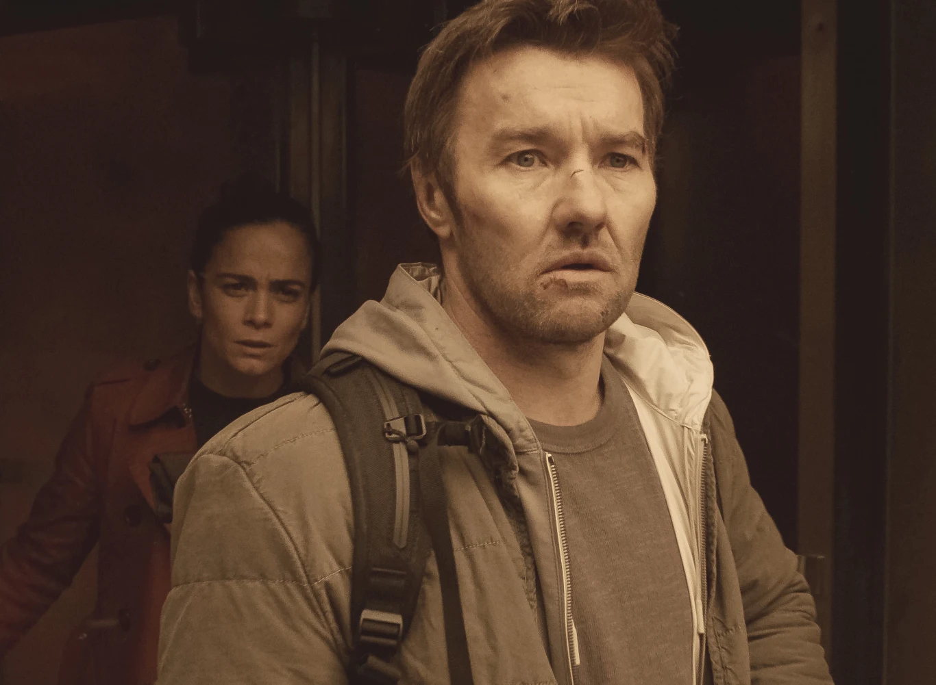 "Mroczna materia": Joel Edgerton i Alice Braga Joel Edgerton z plecakiem na pierwszym planie, za nim Alice Braga w czerwonym płaszczu, oboje patrzą w tym samym kierunku.