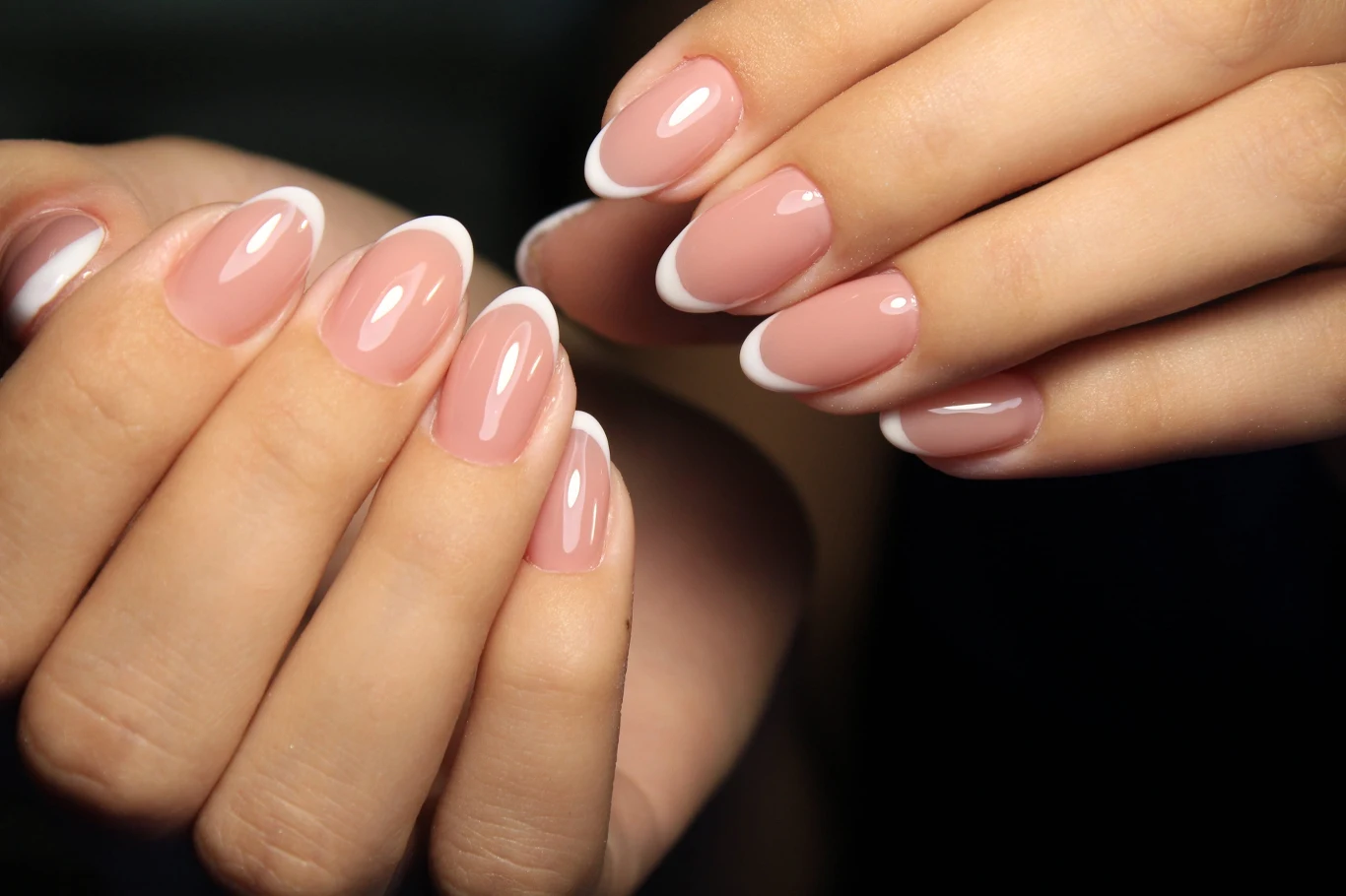 French perlée to hit na lato 2026 Zadbane dłonie z eleganckim manicure francuskim na owalnych paznokciach, z naturalną bazą i białymi końcówkami.