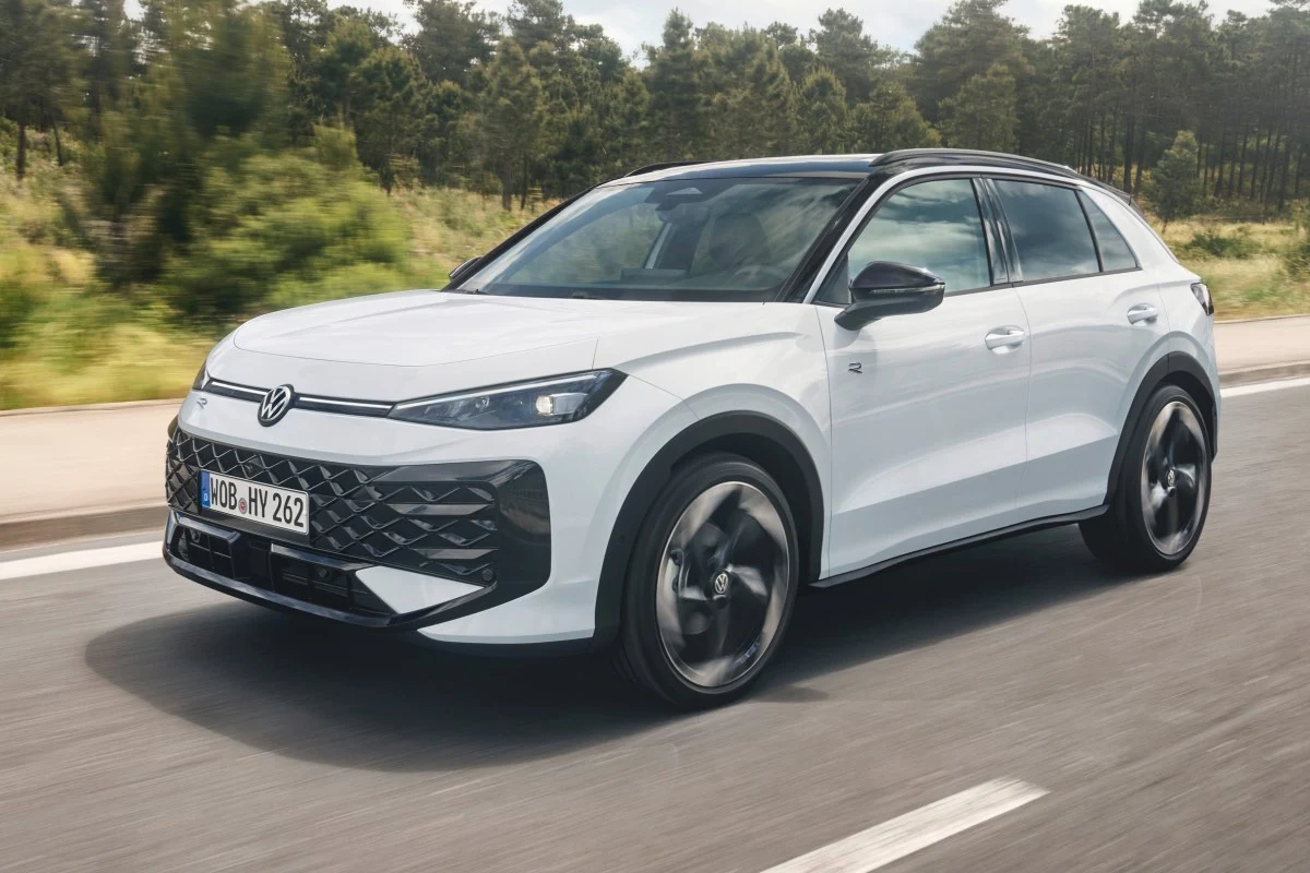 Biały samochód marki Volkswagen poruszający się po asfaltowej drodze, dynamiczna sylwetka SUV-a z czarnym dachem i nowoczesnymi reflektorami, widoczny numer rejestracyjny na przednim zderzaku.
