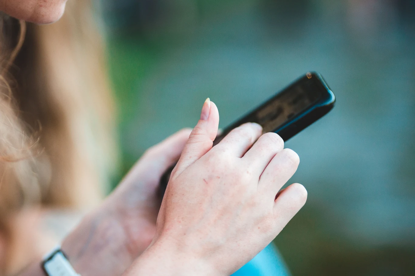 Prezydent podpisał ustawę o zakazie używaniu smartfonów w szkołach i przedszkolach Dłoń trzymająca smartfon, na którym ktoś korzysta z ekranu dotykowego