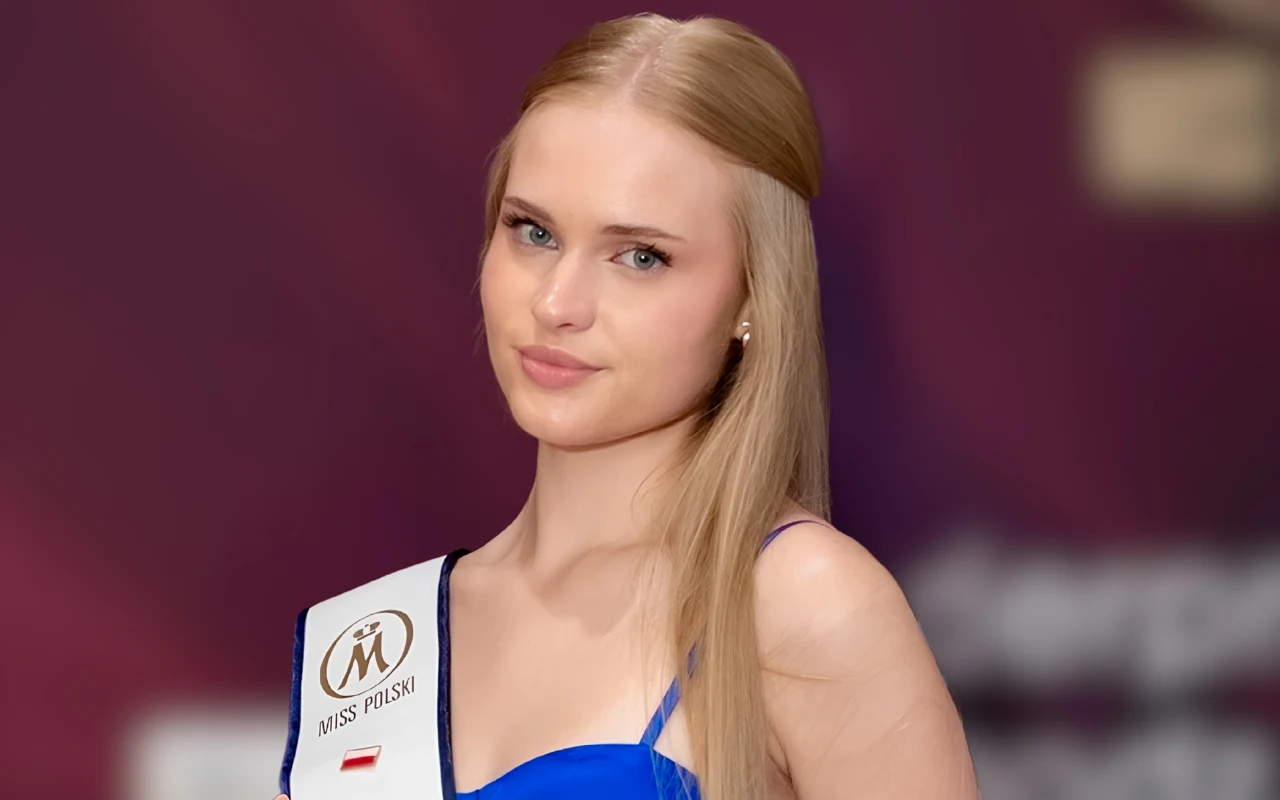 Młoda kobieta z długimi blond włosami ubrana w niebieską sukienkę i szarfę z napisem 'Miss Polski'.