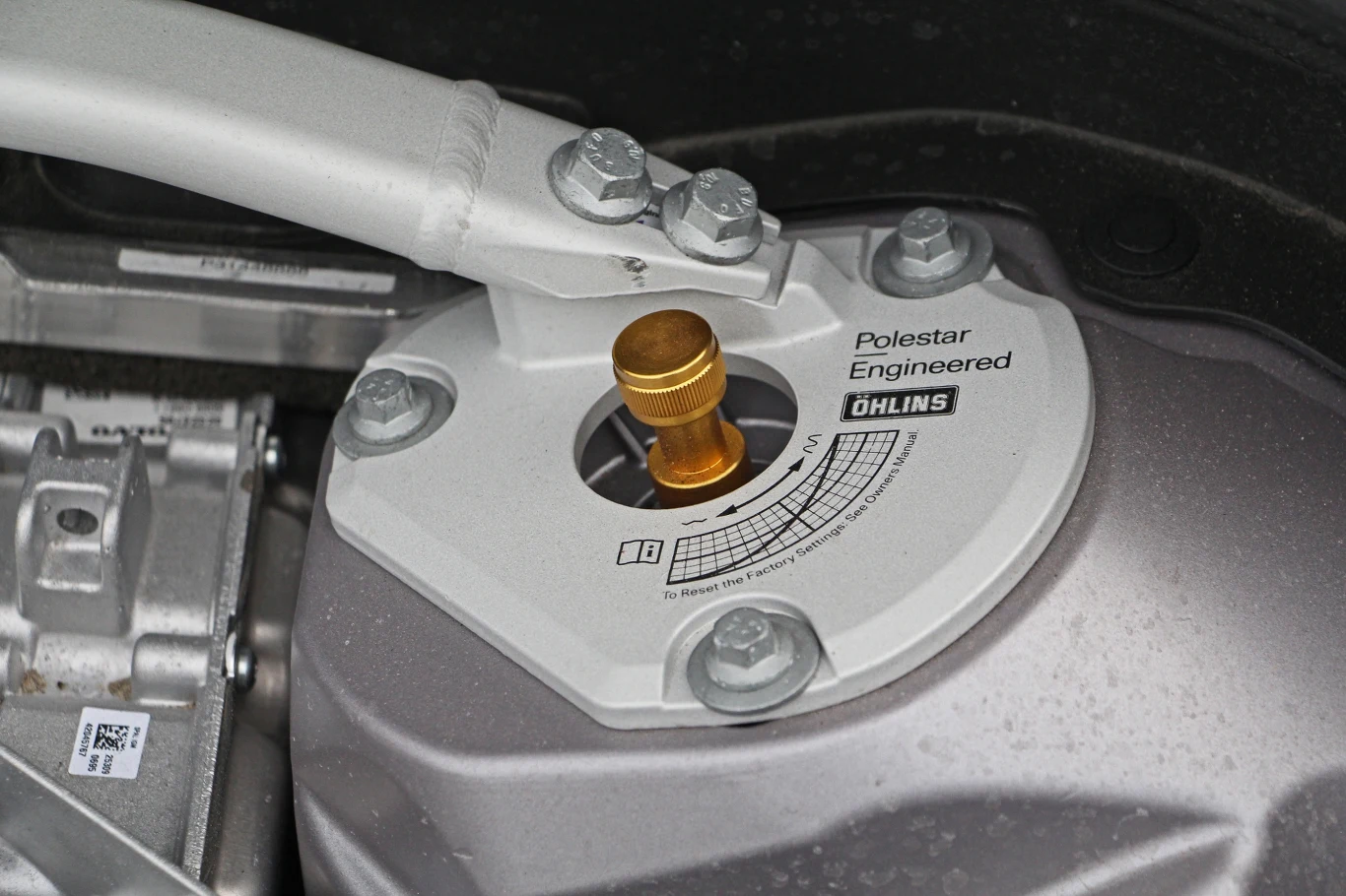 Górne mocowanie amortyzatora oznaczone logotypami Polestar Engineered i Öhlins, centralnie umieszczony złoty regulator oraz precyzyjna skala ustawień zawieszenia.