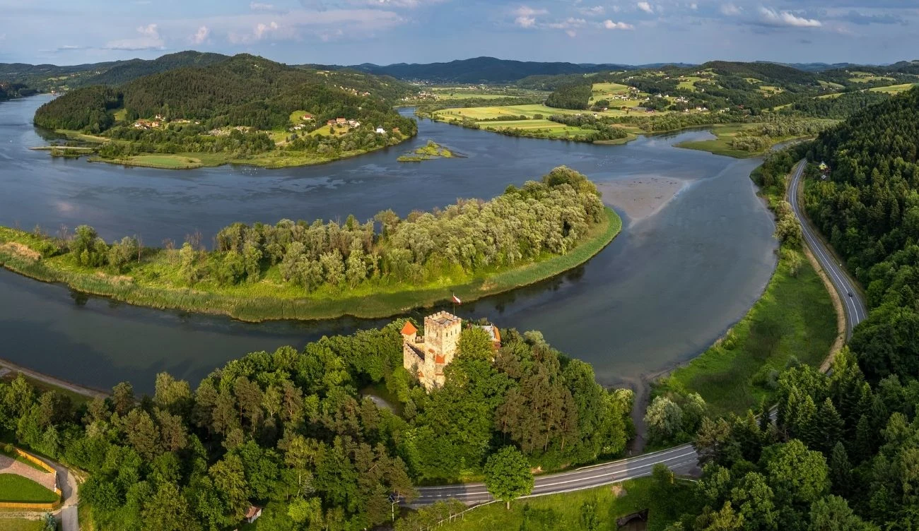 Wokół zamku Tropsztyn krąży wiele legend i opowieści o skarbach Kamienny zamek Tropsztyn otoczony lasem, położony przy zakolu rzeki w zielonym, pagórkowatym krajobrazie.