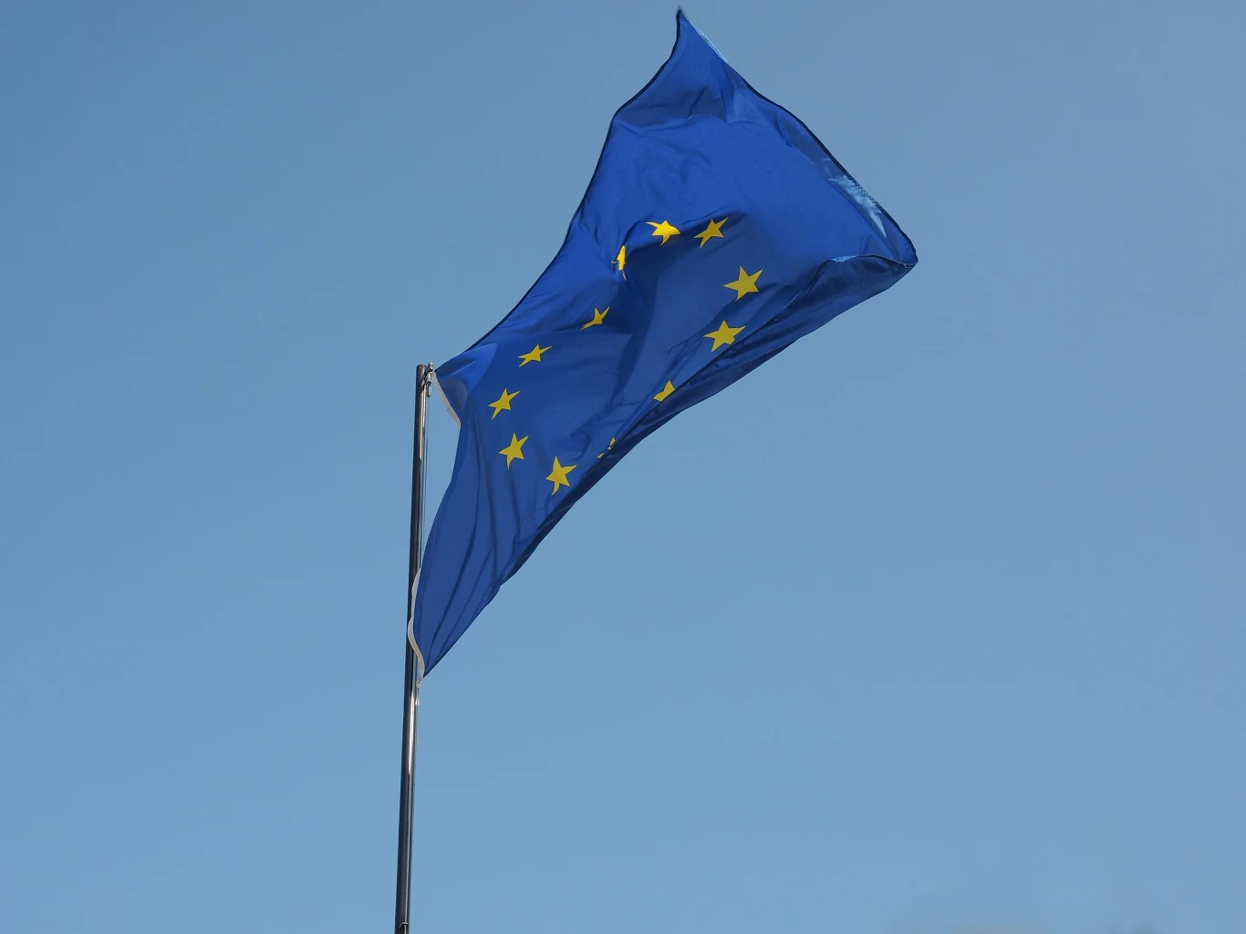 Wchodzą w życie pierwsze przepisy unijnego aktu o sztucznej inteligencji AI Act. Nakładają wysokie kary i wymagają przejrzystości Flaga Unii Europejskiej z dwunastoma złotymi gwiazdami powiewa na tle nieba, symbolizując wprowadzenie AI Act.