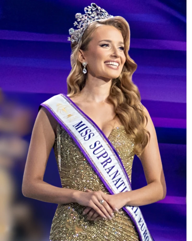 Oliwia Mikulska, Miss Supranational Europe 2026 Młoda kobieta w zdobionej sukni wieczorowej z diamentową koroną na głowie i szarfą z napisem MISS SUPRANATIONAL EUROPE, uśmiechnięta, stojąca na tle fioletowych świateł.