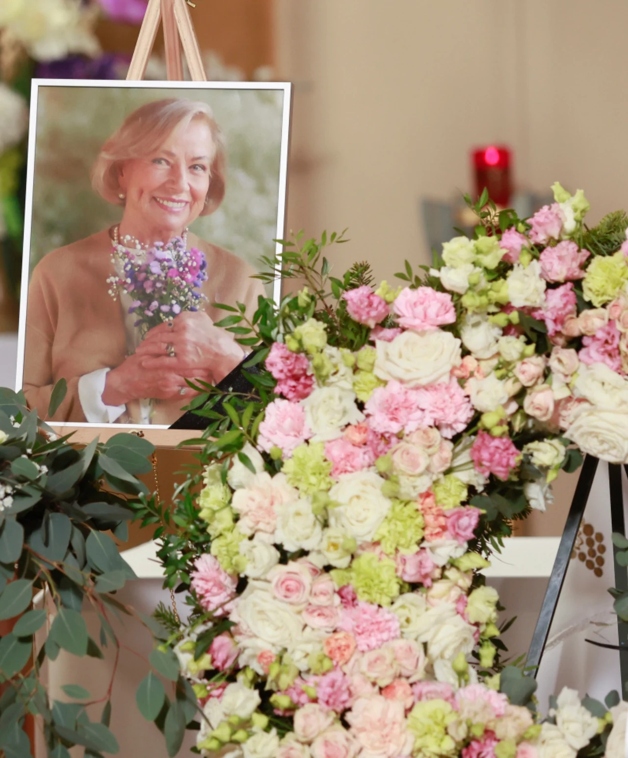 Kadr z pogrzebu Marii Zięby z "Na Wspólnej" Portret starszej kobiety z kwiatami obok dużego, kwiecistego wieńca z różowych, białych i zielonych róż.