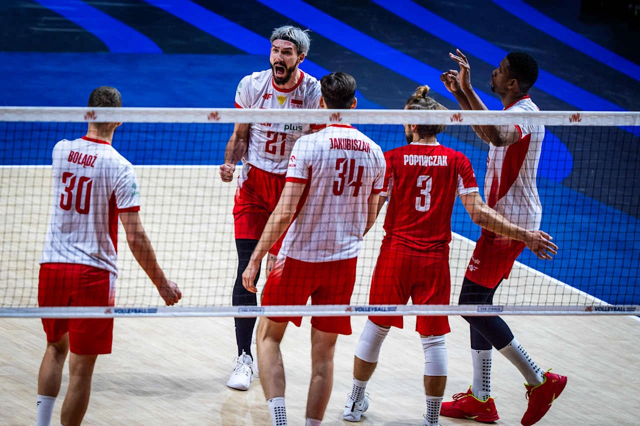 Grupa siatkarzy w biało-czerwonych strojach świętuje zdobycie punktu na boisku podczas meczu.