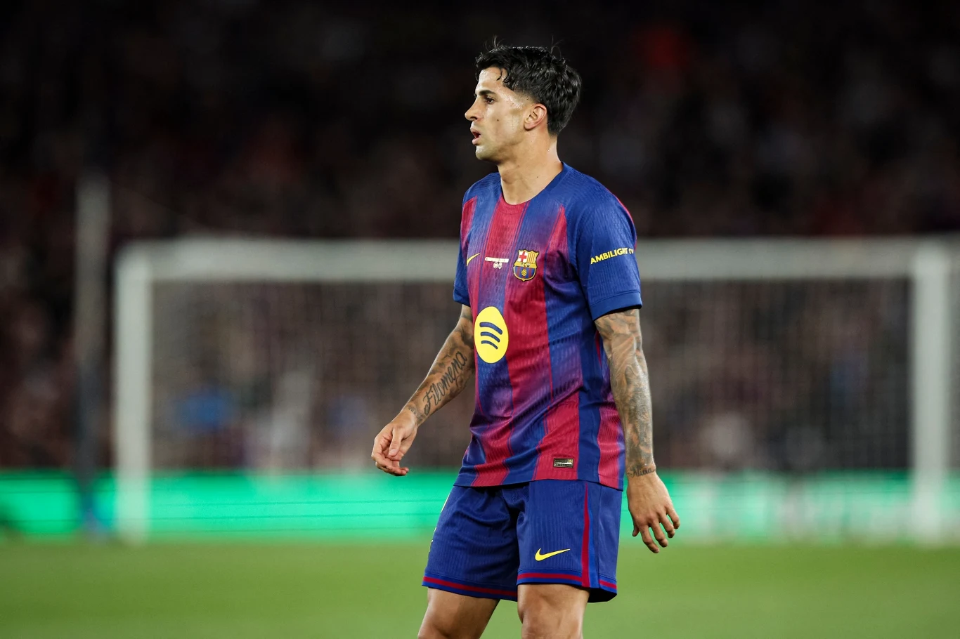 Joao Cancelo Piłkarz w stroju FC Barcelony na stadionie, skierowany w bok, z widocznym logo sponsora na koszulce.