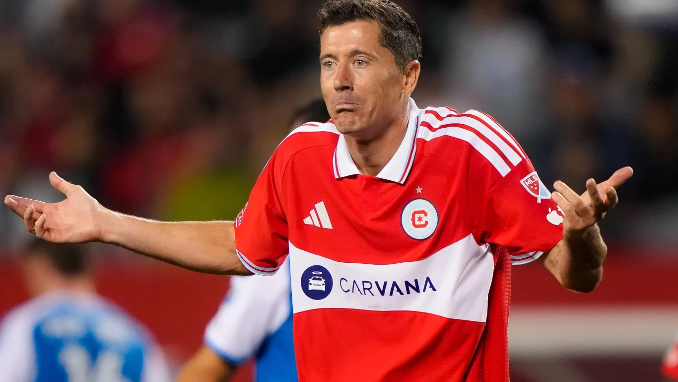 Robert Lewandowski w Chicago Fire Piłkarz w czerwono-białej koszulce z rozłożonymi rękami i wyrazem zaskoczenia na twarzy podczas meczu.
