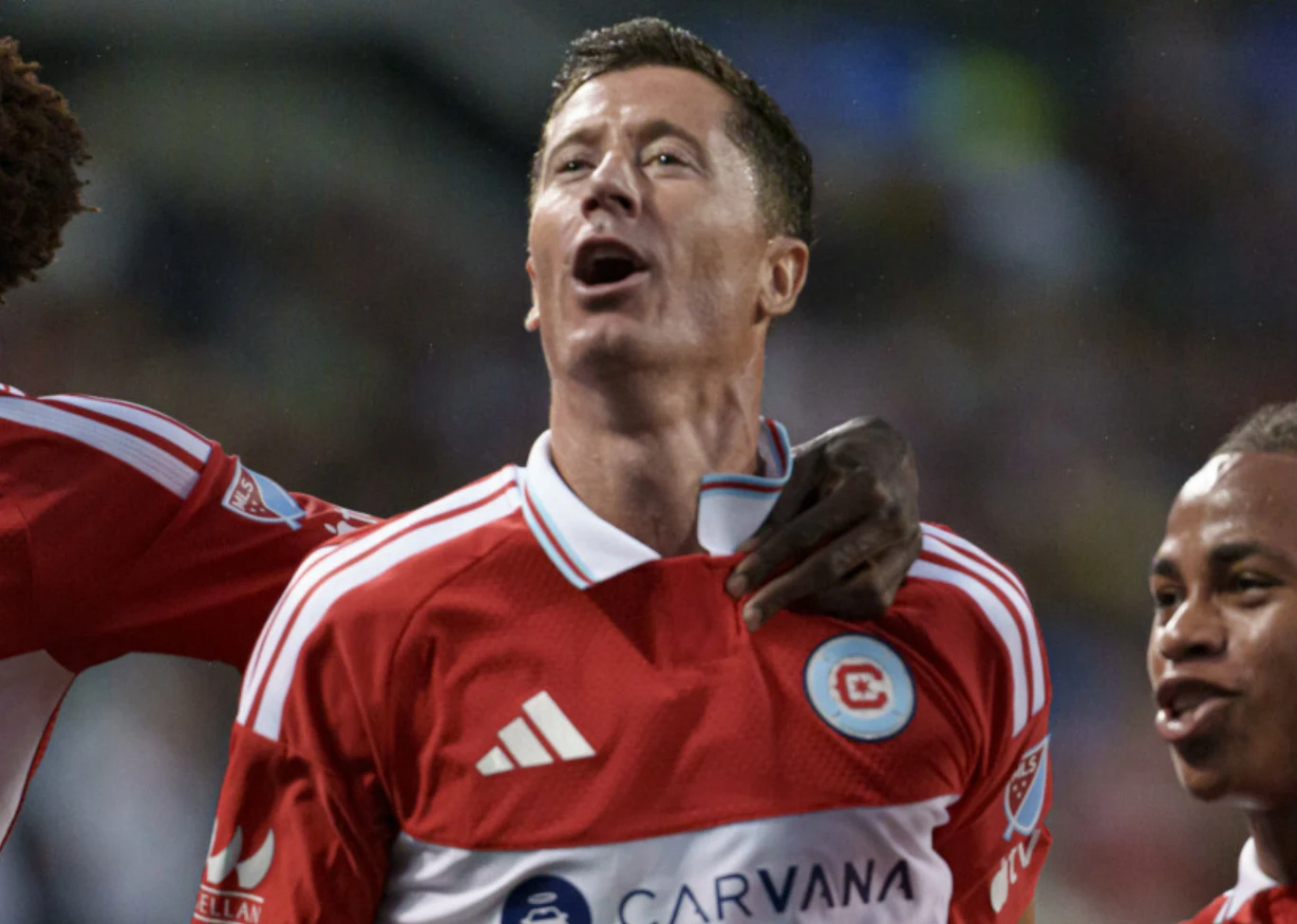 Robert Lewandowski w barwach Chicago Fire Piłkarz w czerwono-białej koszulce drużyny świętujący zdobycie gola z towarzyszącymi mu kolegami z zespołu.