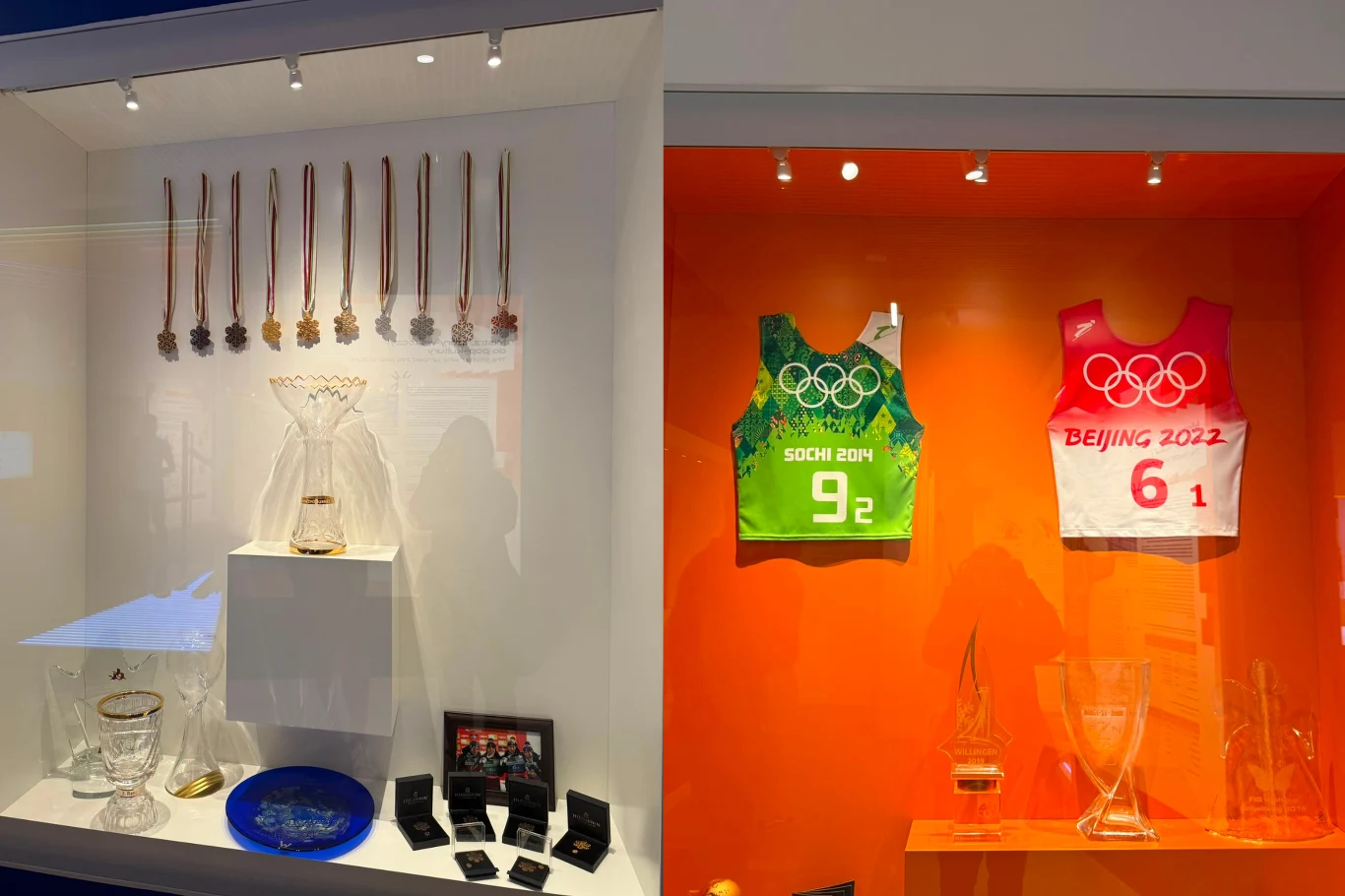 Beskidzkie Centrum Narciarstwa Kolekcja olimpijskich medali, trofeów i gadżetów sportowych, w tym dwa numerowane koszulki startowe z igrzysk w Soczi 2014 i Pekinie 2022, wyeksponowane w podświetlonej gablocie.