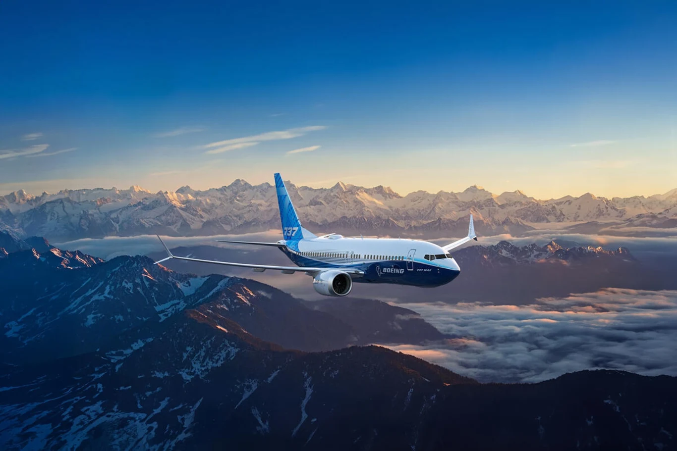 Kamień milowy dla programu 737 MAX. Biało-niebieski samolot Boeing 737-7 MAX lecący nad ośnieżonymi górami w promieniach słońca.