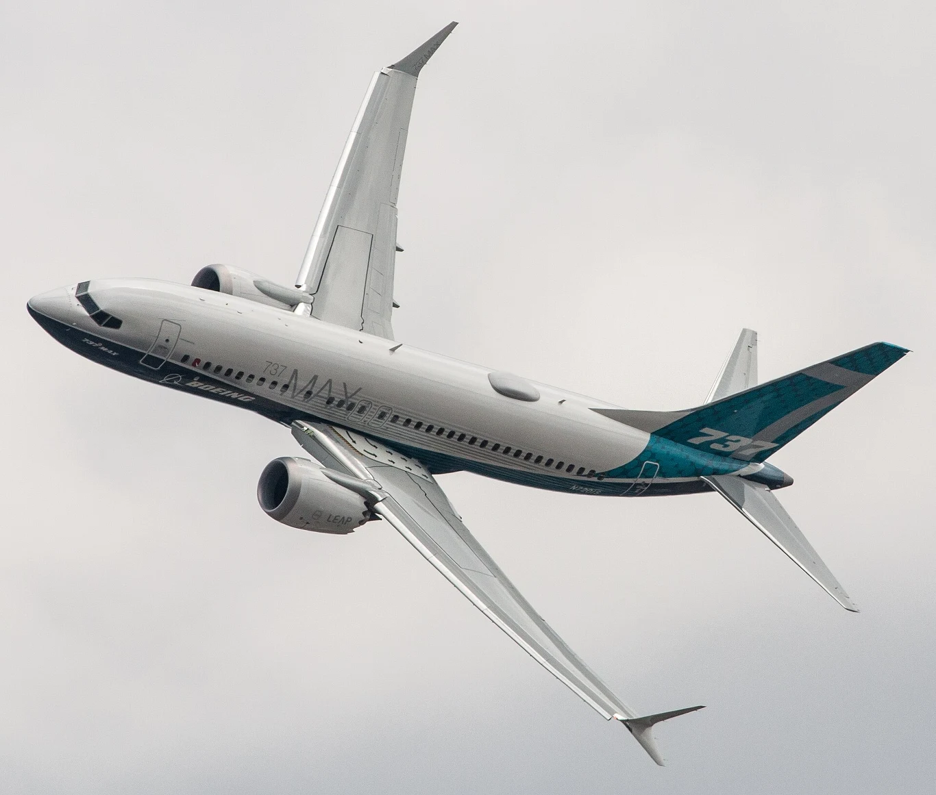 737-7 oferuje zasięg do ok. 7040 km. Dla porównania, 737-8 do 6480 km, 737-9 do 6110 km, a 737-10 do 5740 km. Samolot pasażerski Boeing 737 MAX w locie, widoczny z boku podczas manewru skrętu na tle pochmurnego nieba.