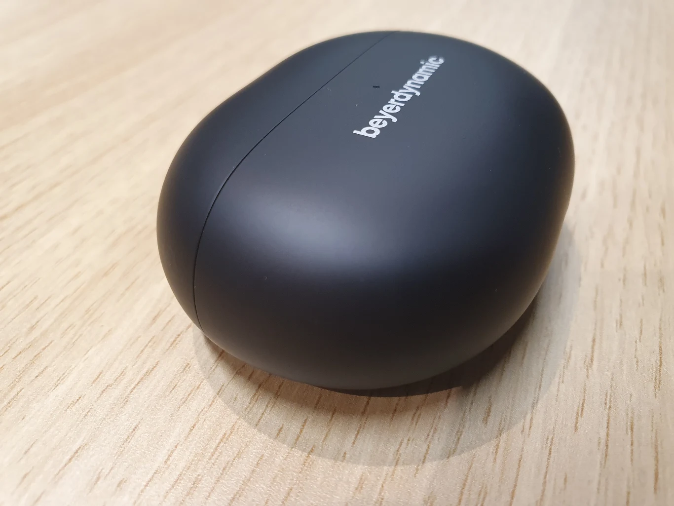 Czarne etui na słuchawki bezprzewodowe z logo beyerdynamic, ustawione na drewnianej powierzchni.