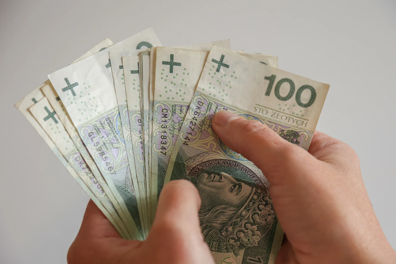 Kto może się ubiegać o świadczenie wspierające? Osoba trzyma w dłoniach banknoty o nominale 100 zł