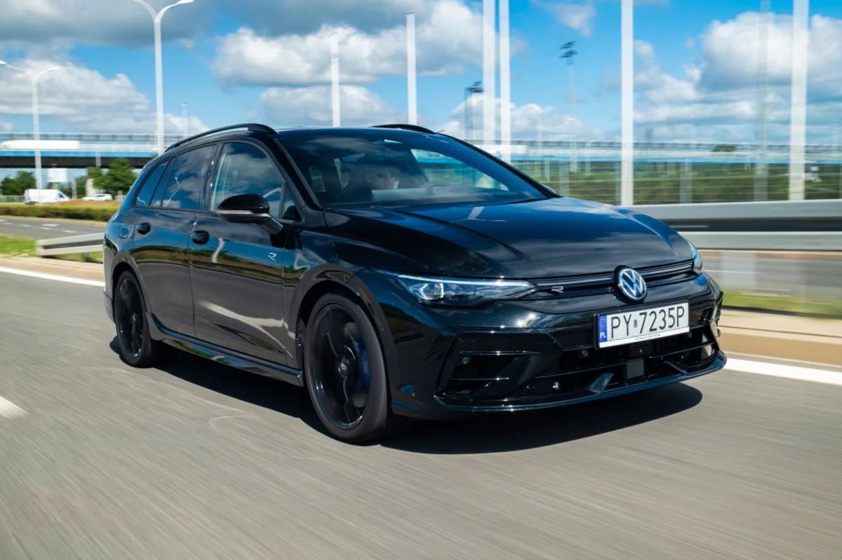 Volkswagen Golf R w wersji kombi potrafi kosztować przeszło ćwierć miliona złotych. Czarny Volkswagen kombi poruszający się dynamicznie po wielopasmowej drodze, sylwetka podkreślona sportowymi felgami i nowoczesnymi liniami nadwozia.