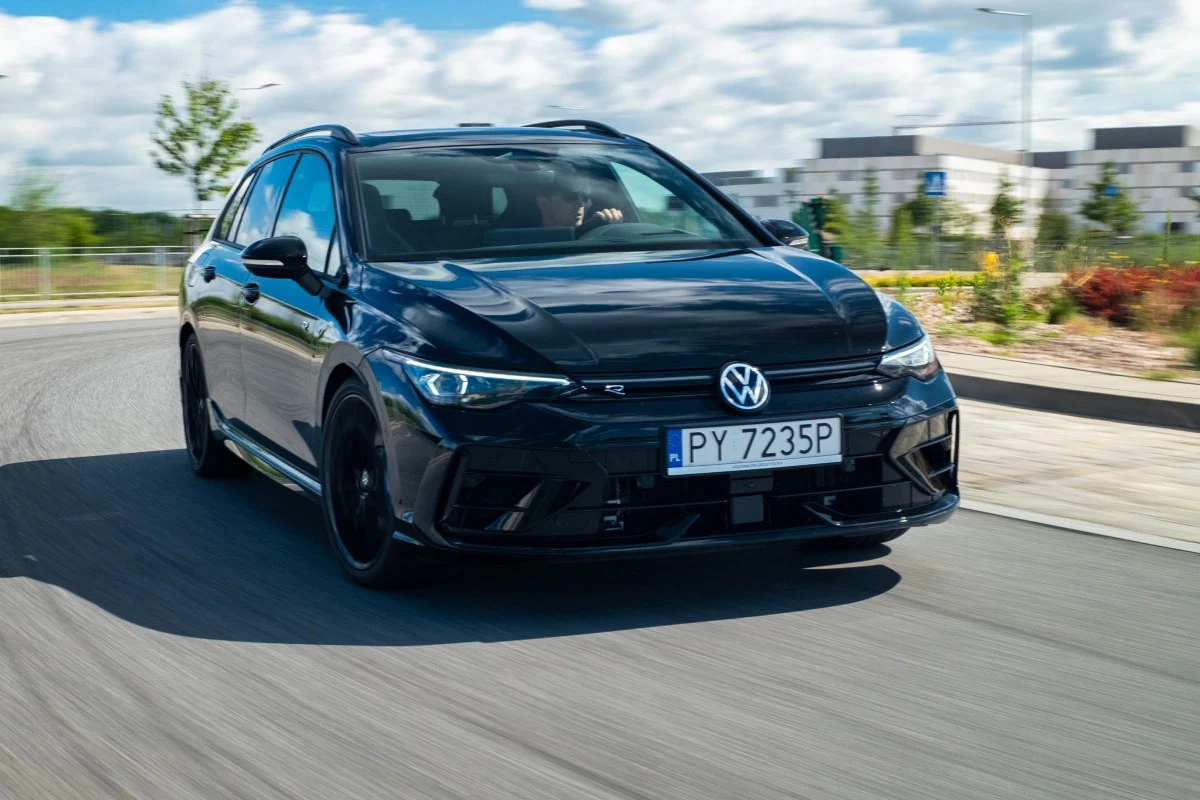 To niepozorne kombi rozpędza się do 270 km/h. Czarny Volkswagen kombi z przyciemnianymi szybami dynamicznie jedzie po jezdni na tle nowoczesnych budynków i zieleni.