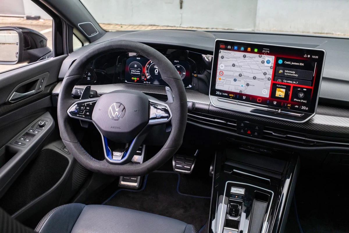 O tym, że to Volkswagen Golf R, mówią m.in. duże manetki za kierownicą Kokpit samochodu Volkswagen z nowoczesną kierownicą wielofunkcyjną, cyfrowym zestawem wskaźników oraz dużym ekranem systemu multimedialnego wyświetlającym mapę nawigacji i menu muzyczne.