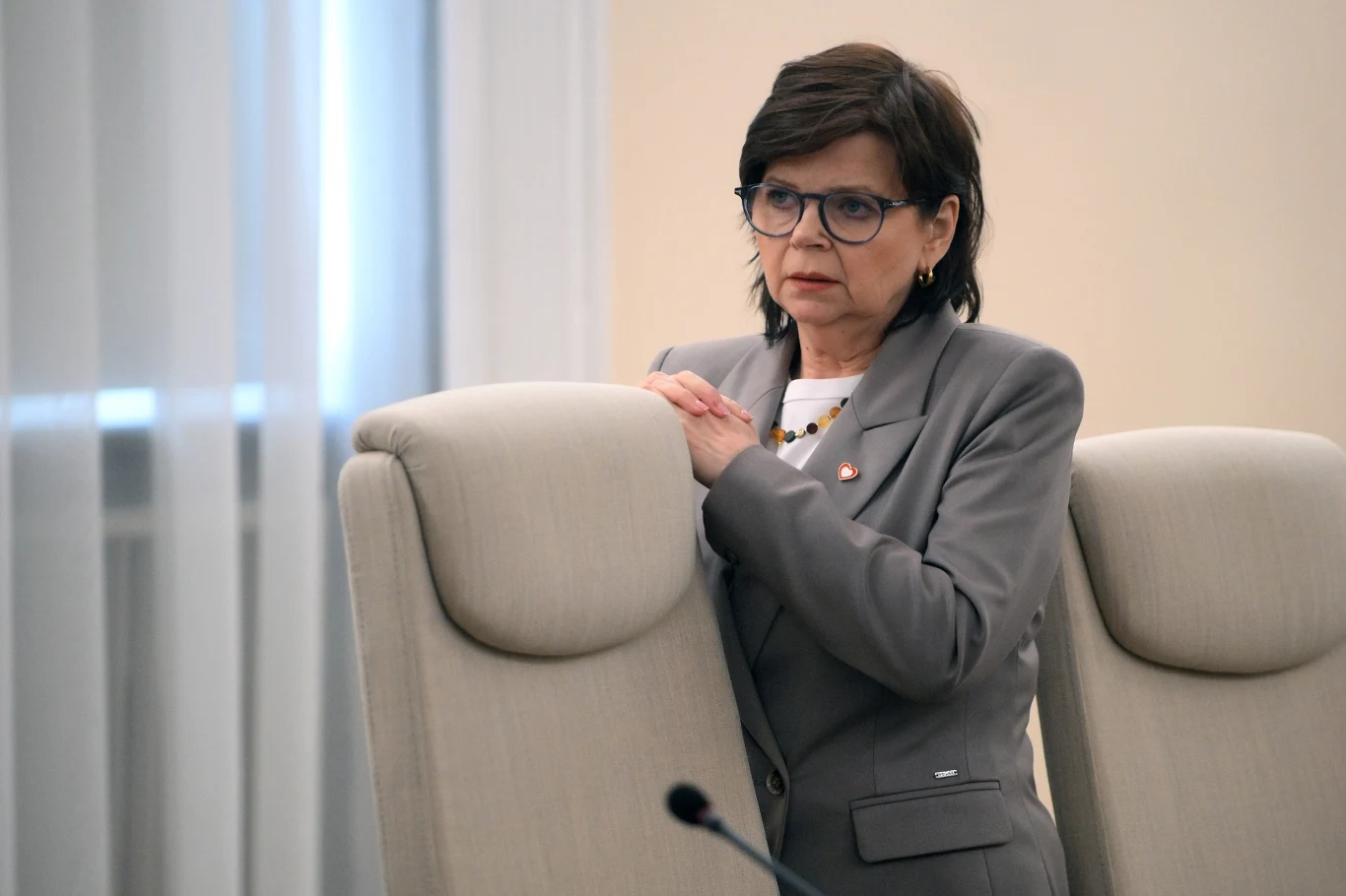 Izabela Leszczyna musi przeprosić Marcina Warchoła Izabela Leszczyna w okularach i szarej marynarce stoi przy jasnym fotelu w urzędowym wnętrzu.