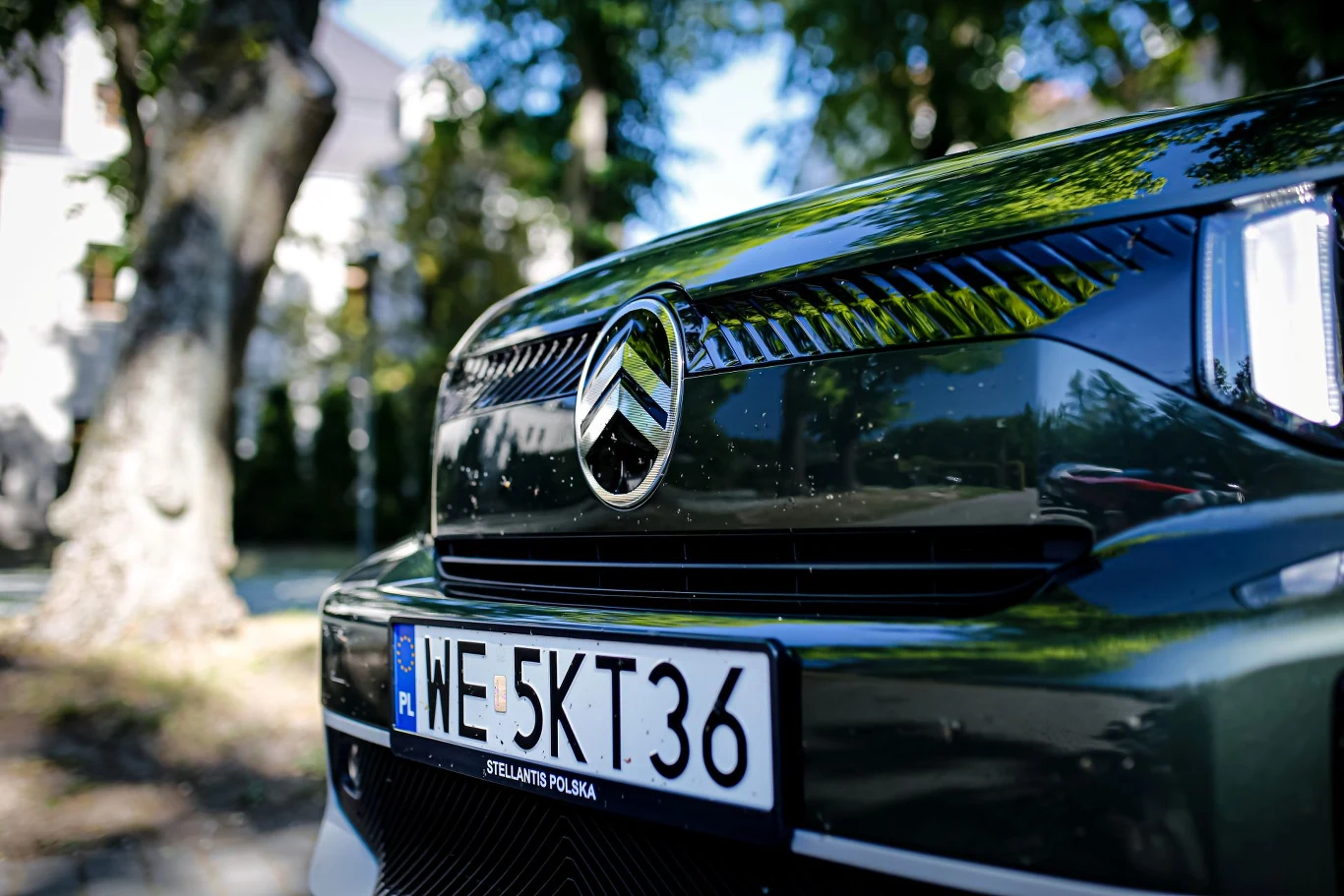 Zbliżenie na przednią część elektrycznego Citroëna z widocznym logo marki oraz tablicą rejestracyjną WE 5KT36.