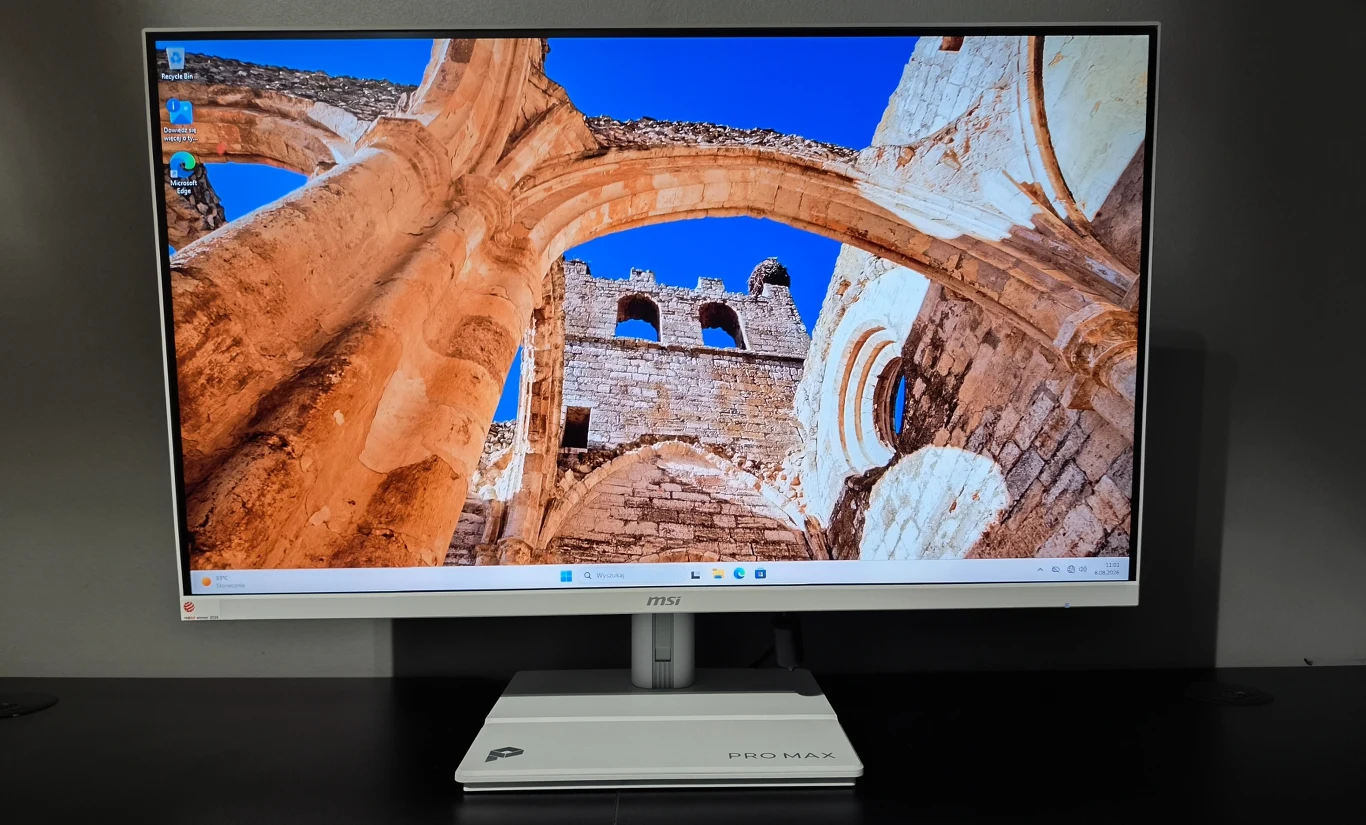 MSI PRO MAX 27P Z MSI PRO MAX 27P Z, biały komputer All-in-One z obrazem kamiennych ruin na ekranie, na czarnej powierzchni.