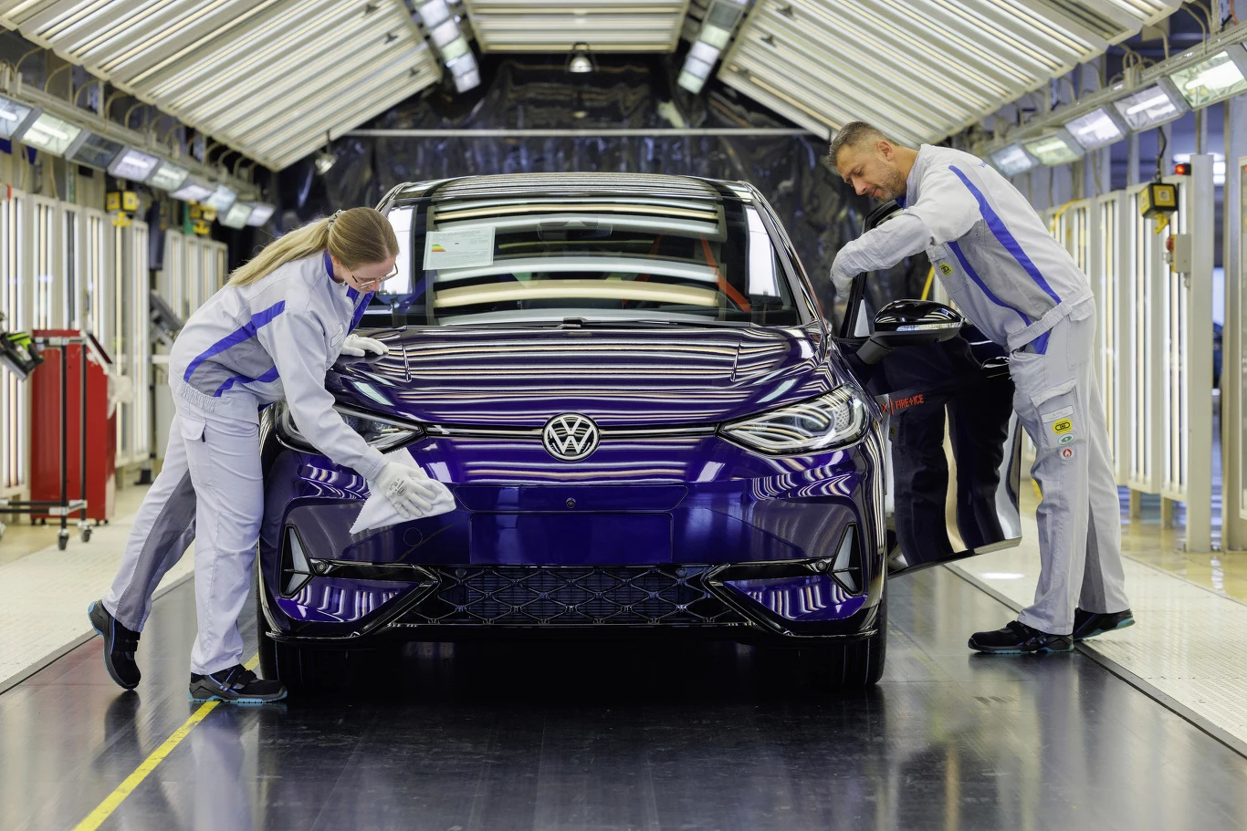Fabryka Volkswagena w Zwickau Pracownicy w kombinezonach polerują niebieskiego Volkswagena w fabryce w Zwickau, jasna hala produkcyjna.