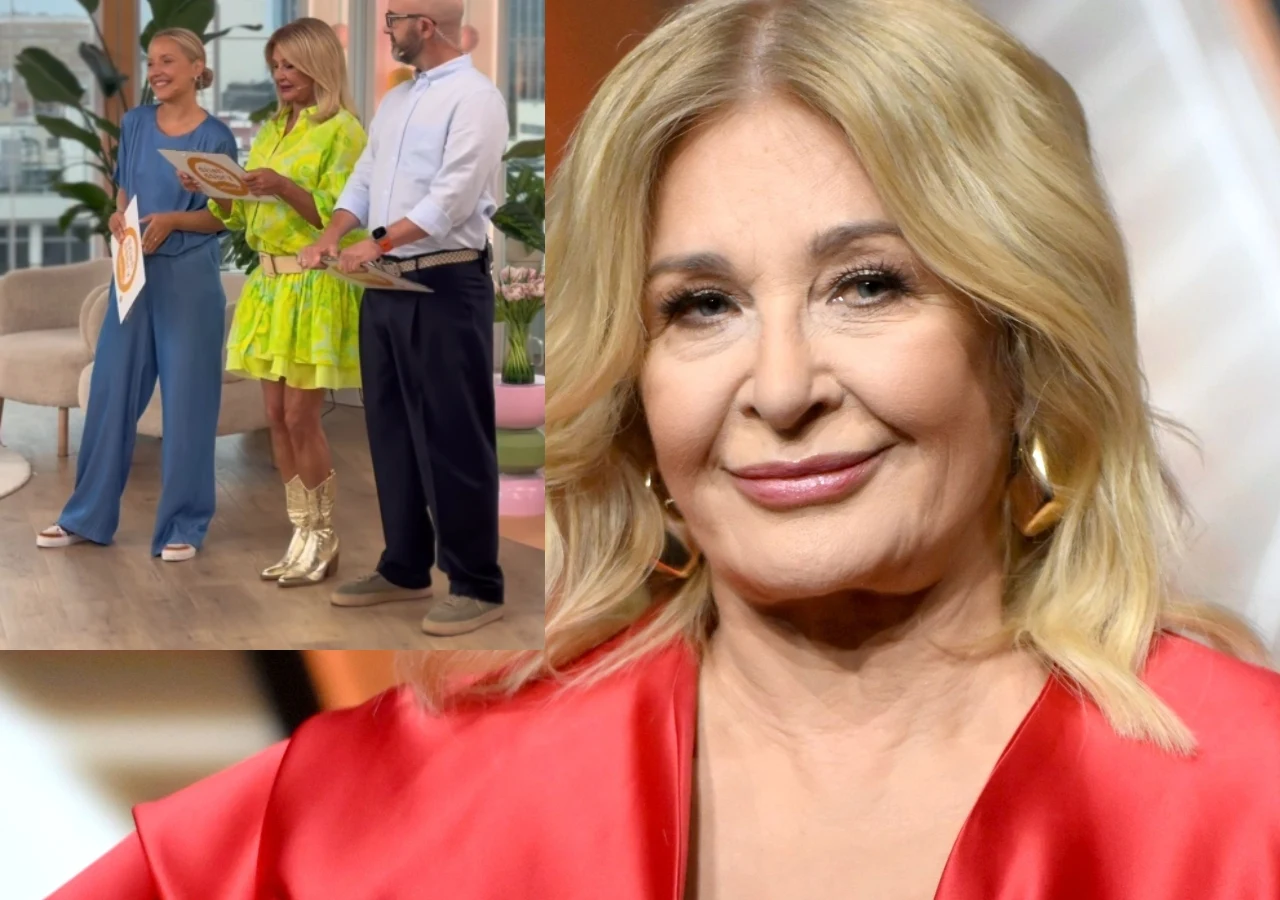 Blondynka w czerwonej, satynowej bluzce stoi z lekkim uśmiechem, w tle widoczne są trzy osoby na planie programu telewizyjnego – dwie kobiety w barwnych stylizacjach i mężczyzna w koszuli, rozmawiający i trzymający akcesoria do gotowania.