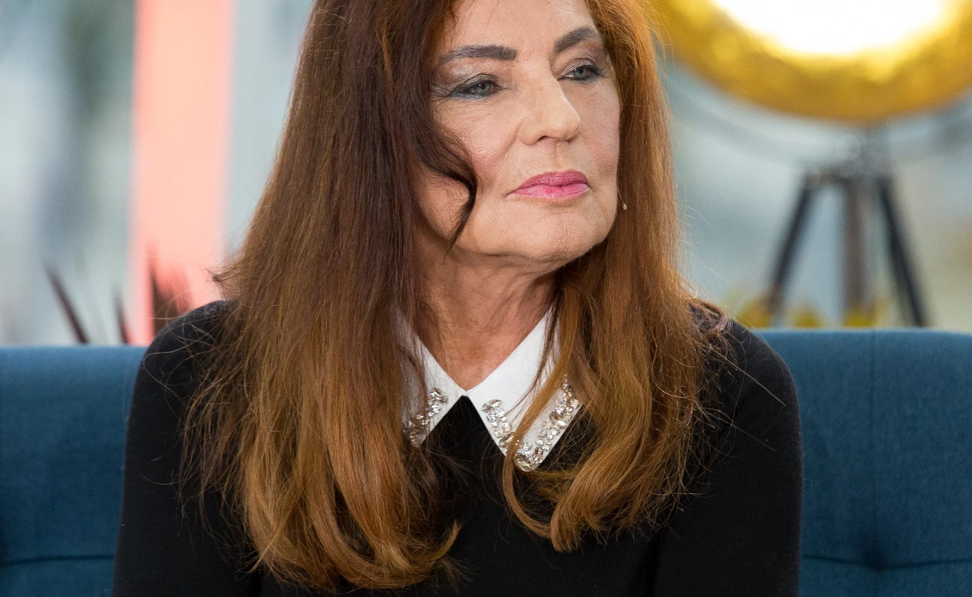 Agnieszka Fitkau-Perepeczko Agnieszka Fitkau-Perepeczko z brązowymi włosami w czarnym swetrze z białym kołnierzykiem siedzi na niebieskiej sofie.