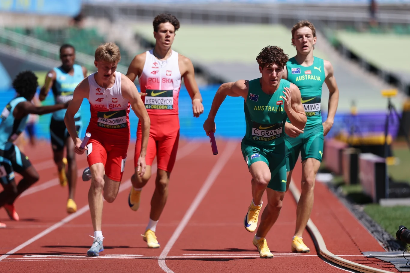Oliwier Frąckowiak (z lewej) ruszył na ostatnią zmianę drugi, za Australijczykiem. I drugi był też na mecie Zawodnicy sztafety lekkoatletycznej rywalizujący na bieżni podczas przekazywania pałeczki, biegnący w skupieniu w reprezentacyjnych strojach swoich krajów.