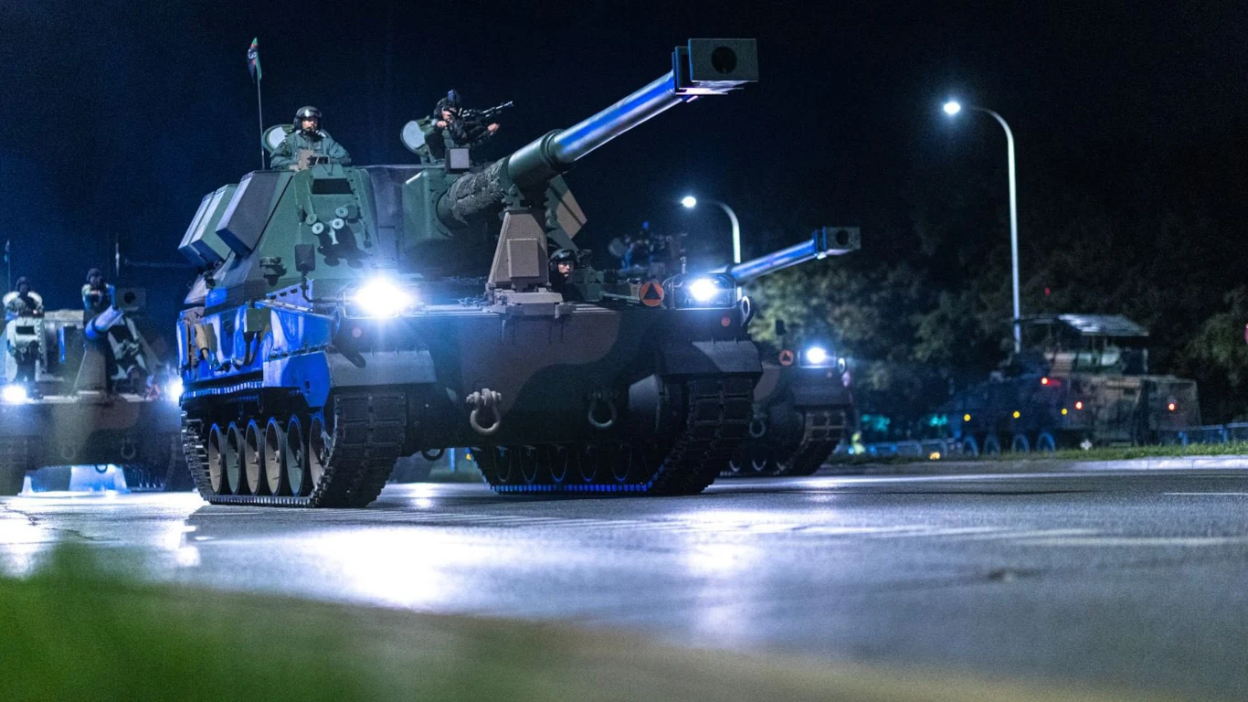 Zbliża się wielka defilada z okazji Święta Wojska Polskiego 15 sierpnia. Oto najrzadsza broń, jaką będzie można zobaczyć. Kolumna ciężkich wojskowych pojazdów opancerzonych z żołnierzami, oświetlona światłami ulicznymi nocą.