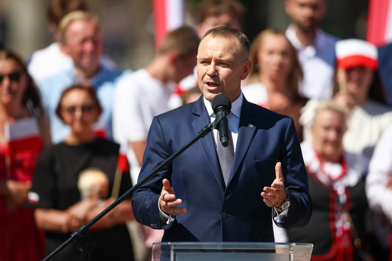 Prezydent Karol Nawrocki Karol Nawrocki podczas spotkania w Skawinie, przemawia zza mównicy, za nim stoją uczestnicy spotkania.
