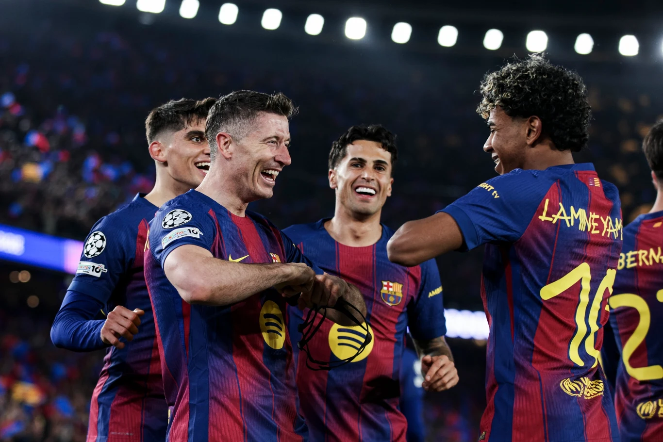 Robert Lewandowski, Joao Cancelo i Lamine Yamal Grupa piłkarzy FC Barcelony w granatowo-bordowych koszulkach cieszy się wspólnie na boisku po udanej akcji podczas meczu.