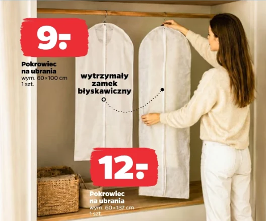 Pokrowce na ubrania od 9 zł. Kobieta w jasnym swetrze zawiesza długie, białe pokrowce na ubrania z wytrzymałym zamkiem błyskawicznym na drążku w szafie; przy dolnej półce znajduje się kosz z wikliny.