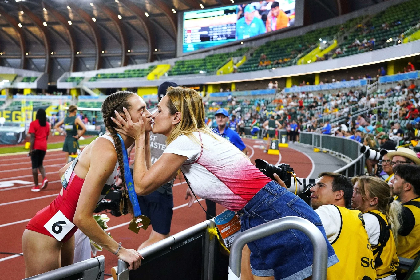 Anastazja Kuś na mecie odbiera gratulacje od mamy Alicji Kuś Zawodniczka w sportowym stroju i z numerem startowym całuje kobietę stojącą za barierką, celebrując emocjonujący moment po zawodach lekkoatletycznych na stadionie.